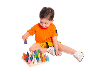 A beautiful European boy plays with wooden Montessori toys on a white background. Child 2.5 years old. Montessori pedagogy, didactic materials. Development and training of preschool children.