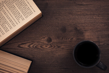 Book and coffee mug on a wooden background, rustic and homely feel.