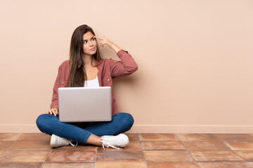 Teenager student girl sitting on the floor with a laptop with problems making suicide gesture