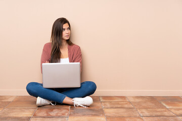 Teenager student girl sitting on the floor with a laptop portrait