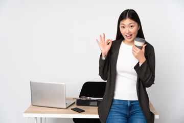 Business asian woman in her workplace isolated on white background showing ok sign and thumb up gesture
