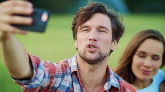 Portrait of happy family using smartphone for video chat in meadow