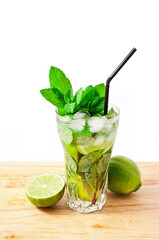 Cocktail mojito with mint leaves, lime and ice on a cutting board isolated on a white background.