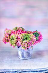 A beautiful bouquet of spring flowers on a pink background on the table with a tablecloth. Pastel colors.
