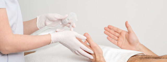 Obraz na płótnie Canvas Nurse hand sanitizing hands of male patient in the hospital. Coronavirus protection concept.