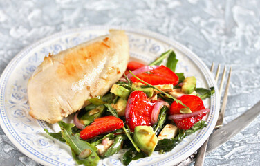 food without carbohydrates - fried chicken breast and salad with strawberries, cheese, avocados, onions and herbs, dressed with oil and balsamic. keto diet. rich in proteins. lunch for keto.