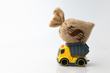 The yellow, gray truck delivering carrying a bag of money on the pickup on a white background has a symbol dollar at the bag with a copy space on the left side. Concept business and financial. © Chaiwat