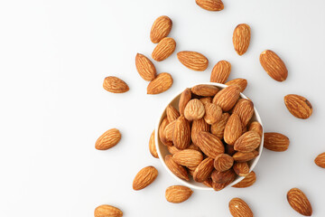 Almonds nut seed in white bowl flat lay top view heap on white background with copy space on the left. Snack whole healthy food is useful to help neutralize free radicals and provide energy.