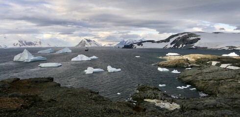 Fototapeta na wymiar Bay with ship, icebergs, mountains in antarctic landscape, Antarctica