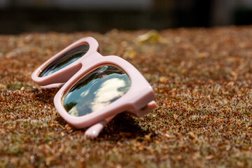 Pair of pink sunglasses lying on the ground