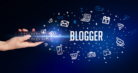 hand holding wireless peripheral with BLOGGER inscription, social media concept