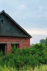 Fototapeta premium Abandoned brick house in the village. A grassy house.