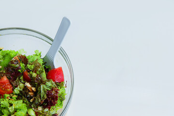 fresh vegetable salad in a glass plate on the side on a white background and there is a revenge for...