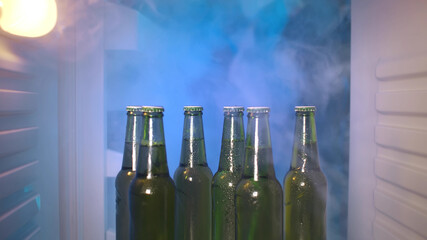 Cold beer bottles on the shelf of the fridge full of steam. Ready for hot energetic party. View...