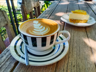 Coffee late art and a slice of lemon cheesecake dessert for food and drinks