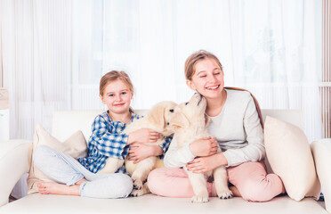 Smiling sisters sitting with puppies