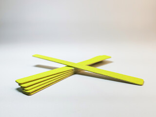 Set of yellow disposable nail files on a gray gradient background. Tools for independent manicure...