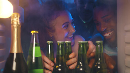 Group of friends taking cool beer from refrigerator