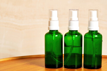 Green bottles with cosmetic liquid spray on the wooden table. Herbal medicine and traditional body care. Copy space for advertisement text