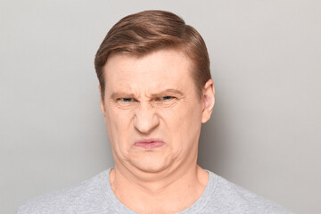 Portrait of funny man grimacing from disgust and squeamishness