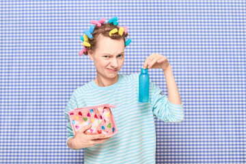 Girl with colorful hair curlers on head is holding cosmetic product