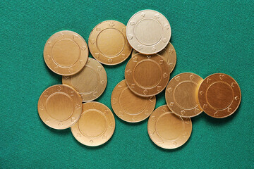 Heap of the golden coins and gambling chips on the green casino poker table. Gambling and casino backgrounds and textures
