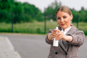 Stylish girl in an elegant suit holds bottle with an antiseptic. The concept of health care during a pandemic