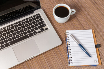 local de trabalho em casa, com bloco de anotações uma caneta um cafe e um laptop