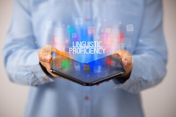 Young man holding a foldable smartphone with LINGUISTIC PROFICIENCY inscription, educational concept