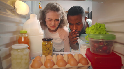 Young couple feeling bad smell from fridge in kitchen