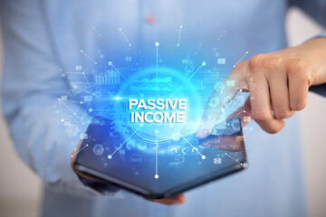 Businessman holding a foldable smartphone with PASSIVE INCOME inscription, new business concept