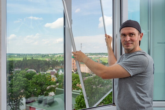 A Contractor Worker Installing Mosquito Wire Screen On House Plastic Windows To Protect From Insects.