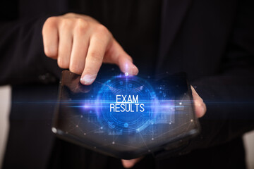 Naklejka premium Young man holding a foldable smartphone with EXAM RESULTS inscription, educational concept
