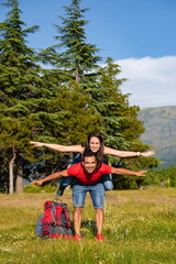 Couple of hikers in the mountains the man catches the girl on the back and the two with open arms
