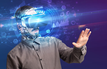 Businessman looking through Virtual Reality glasses with VIRTUAL inscription, innovative technology concept