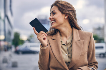 Joyous female holding a smartphone with one hand