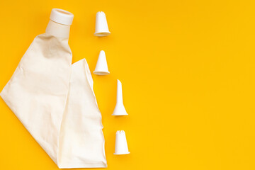 Empty White pastry bag and nozzles lie on a yellow background. The view from the top. Creative layout for advertising and cooking blog. Horizontal position.