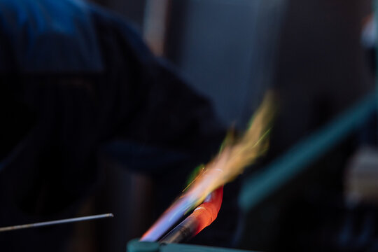 Flame of a copper welding machine heats a copper pipe in a workshop