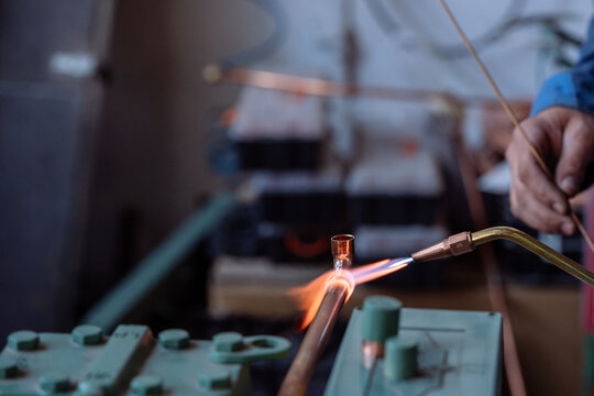 Flame of a copper welding machine heats a copper pipe in a workshop