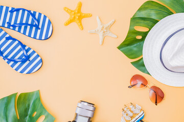 Flat lay composition with a summer hat and flip flops on a yellow background