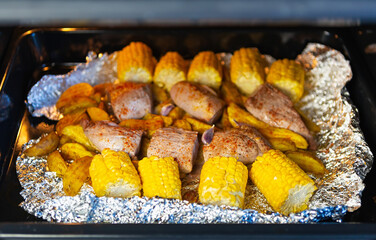 Corn,pork meat and potato with rosemary spice baking in oven at home for dinner meal.Delicious...