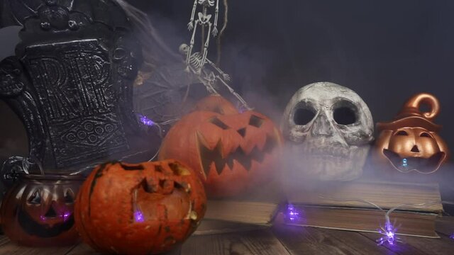 Classic Halloween symbols pumpkins and skulls are filled with smoke slow motion. Theme of celebration of Day of dead and autumn holidays. Concept decorations handmade mystical and religious traditions