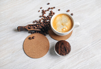 Still life with coffee. Coffee cup, coffee beans, beer coaster and ground powder on light wood...