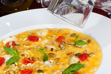 Rice soup with pumpkin seeds, cereals and tomatoes in a white bowl. As backdrop for menus, cookbooks, advertisements and other culinary projects