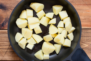 Step by step cooking vegetable stew with turkey, step 2 - chopped raw potatoes in a pan, top view, selective focus