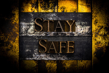 Stay Safe text formed with real authentic typeset letters on vintage textured silver grunge copper and gold background