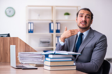 Young male businessman reading books at workplace