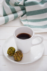A cup of coffee and pistachio candies