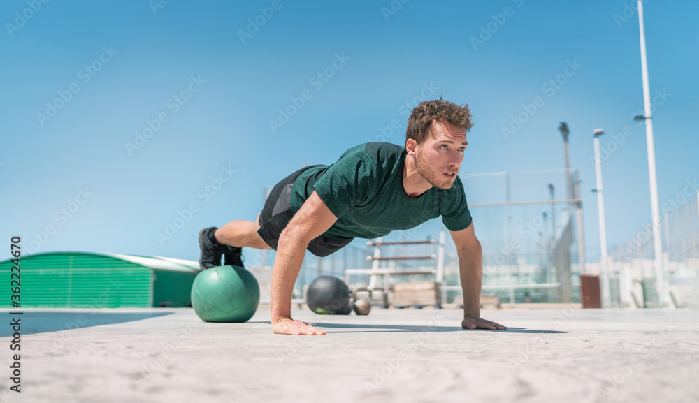 Wall mural fit exercises man strength training core doing balance push-ups workout at outdoor gym balancing on 