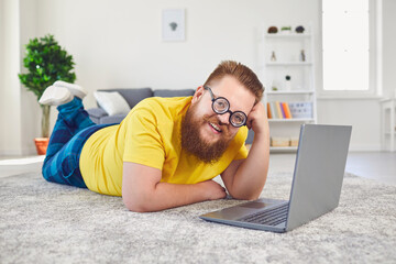 Work online at home office. Funny man works online communicates video chat call using laptop lying...